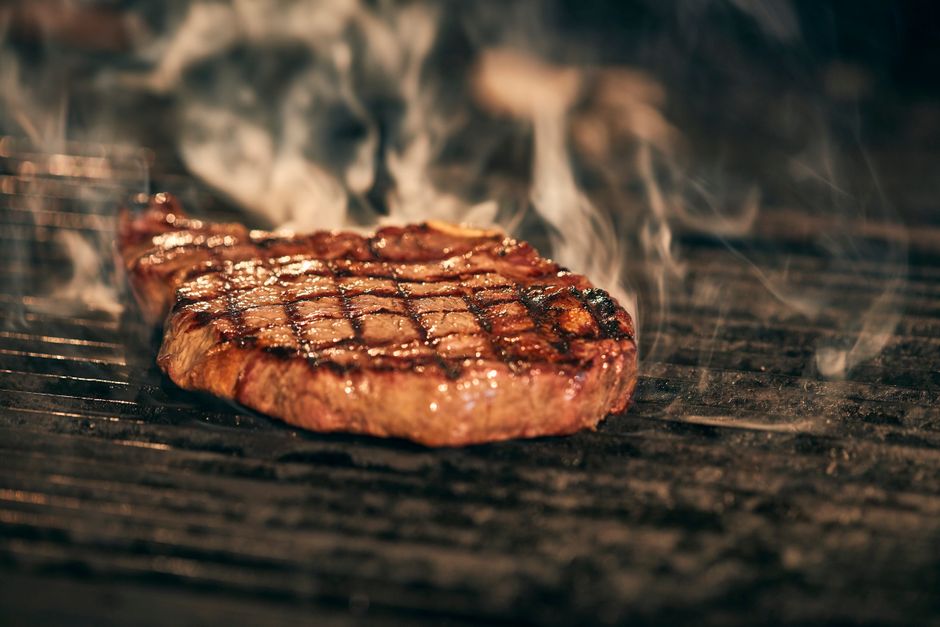 Grilovaný steak na roštu s plameny v pozadí